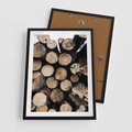 Plakat w ramie 50x70 - Siła Drewna - ścięte drewno, belki drewna ułożone jedna na drugiej - rama czarna