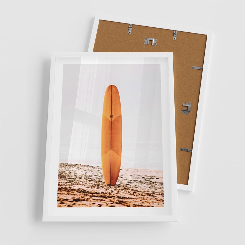 Plakat w ramie 50x70 - Deska w Piasku: Gotowa na Fale - plaża, pomarańczowa deska surfingowa wbita w piasek - rama biała