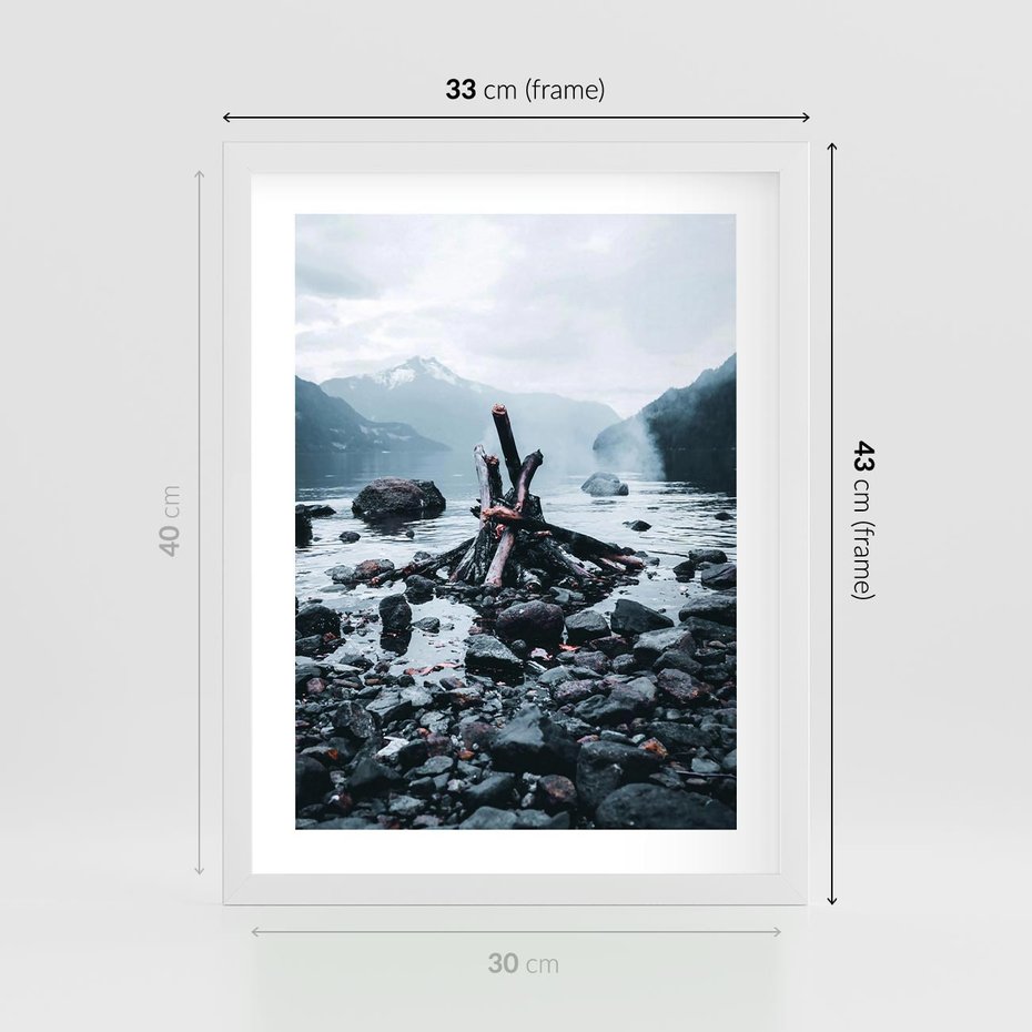 Plakat w ramie 30x40 - To ujęcie jeziora w górach z zgaszonym ogniskiem nad brzegiem, tworząc atmosferę spokoju i refleksji w otoczeniu przyrody. - jezioro w górach, zgaszone ognisko - rama biała