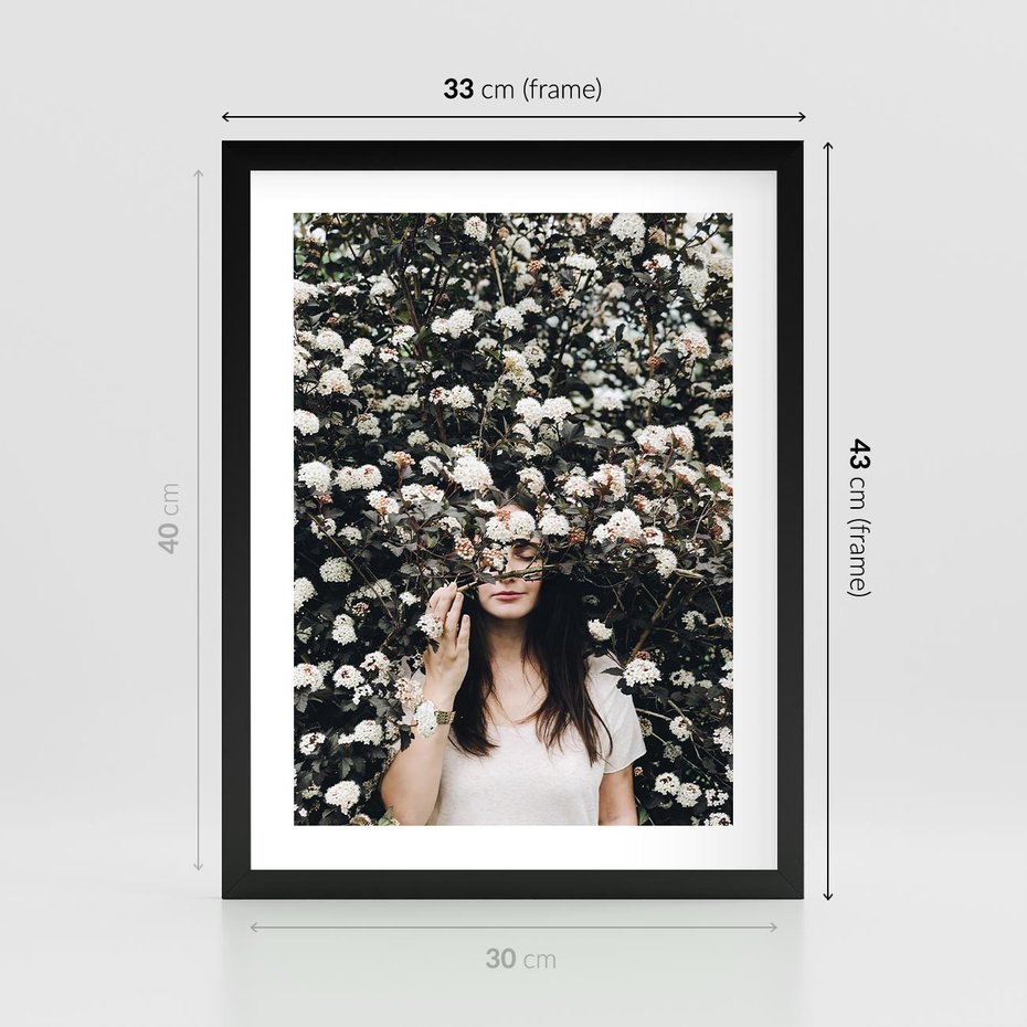 Plakat w ramie 30x40 - Kobieta w Krzewie Kwiatów - krzak z kwiatami, schowana za nim kobieta - rama czarna