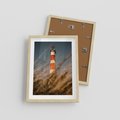 Plakat w ramie 30x40 - Magia nadmorskiego światła - latarnia morska, ujęcie z za trawy - rama drewno