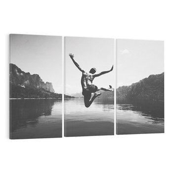 Obraz na płótnie 120x80 - Beztroska Chwila - czarno biała fotografia, mężczyzna wesoło wskakuje do keziora w górach