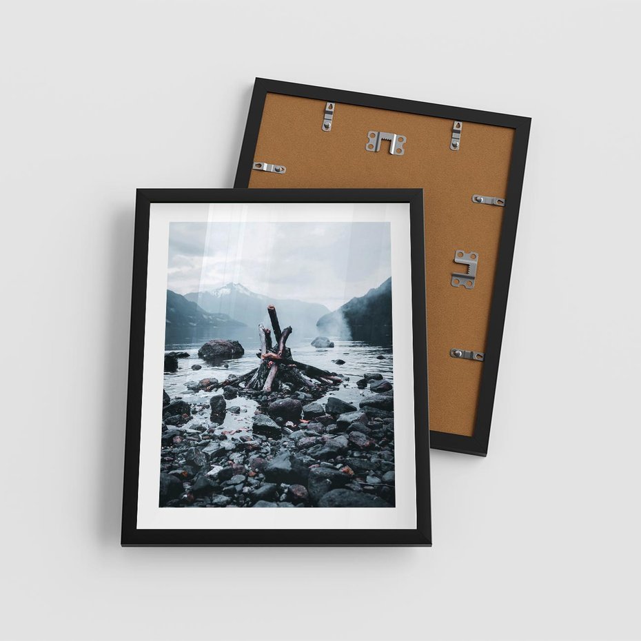 Plakat w ramie 40x50 - To ujęcie jeziora w górach z zgaszonym ogniskiem nad brzegiem, tworząc atmosferę spokoju i refleksji w otoczeniu przyrody. - jezioro w górach, zgaszone ognisko - rama czarna