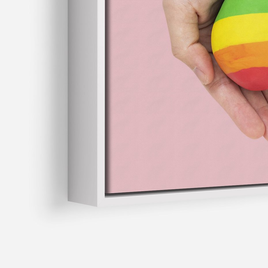 Obraz w ramie 80x120 - Miłość na Dłoniach - zdjęcie, dłonie trzymają ulepione tęczowe serce - rama biała