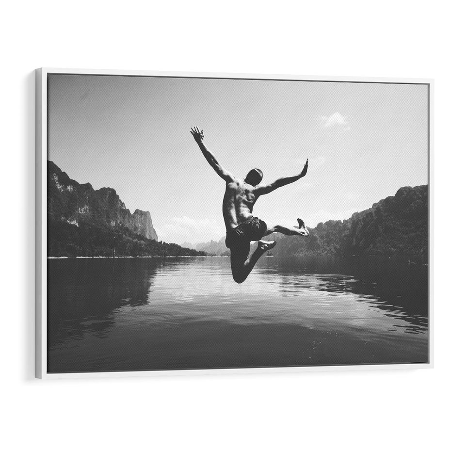 Obraz w ramie 70x50 - Beztroska Chwila - czarno biała fotografia, mężczyzna wesoło wskakuje do keziora w górach - rama biała