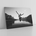 Obraz na płótnie 70x50 - Beztroska Chwila - czarno biała fotografia, mężczyzna wesoło wskakuje do keziora w górach