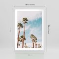 Plakat w ramie 50x70 - Tropikalna Sielskość: Palmy i Błękitne Niebo - palmy na tle błękitnego nieba - rama biała