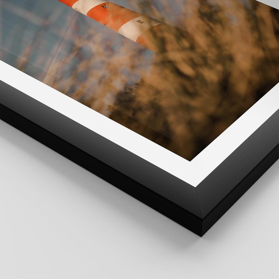 Plakat w ramie 30x40 - Magia nadmorskiego światła - latarnia morska, ujęcie z za trawy - rama czarna