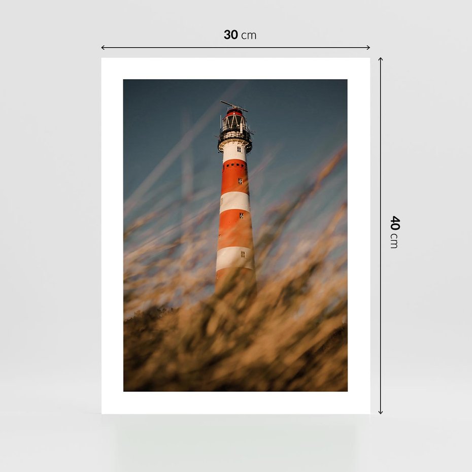 Plakat bez ramy 30x40 - Magia nadmorskiego światła - latarnia morska, ujęcie z za trawy