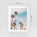Plakat w ramie 40x50 - Tropikalna Sielskość: Palmy i Błękitne Niebo - palmy na tle błękitnego nieba - rama biała