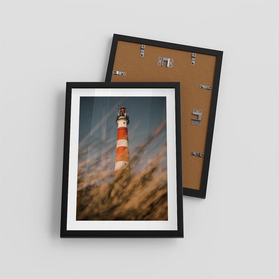 Plakat w ramie 30x40 - Magia nadmorskiego światła - latarnia morska, ujęcie z za trawy - rama czarna