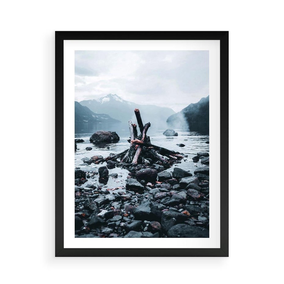Plakat w ramie 50x70 - To ujęcie jeziora w górach z zgaszonym ogniskiem nad brzegiem, tworząc atmosferę spokoju i refleksji w otoczeniu przyrody. - jezioro w górach, zgaszone ognisko - rama czarna