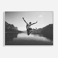 Obraz w ramie 70x50 - Beztroska Chwila - czarno biała fotografia, mężczyzna wesoło wskakuje do keziora w górach - rama biała