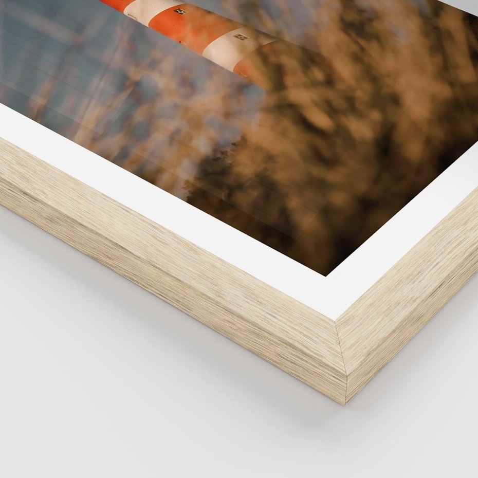 Plakat w ramie 40x50 - Magia nadmorskiego światła - latarnia morska, ujęcie z za trawy - rama drewno