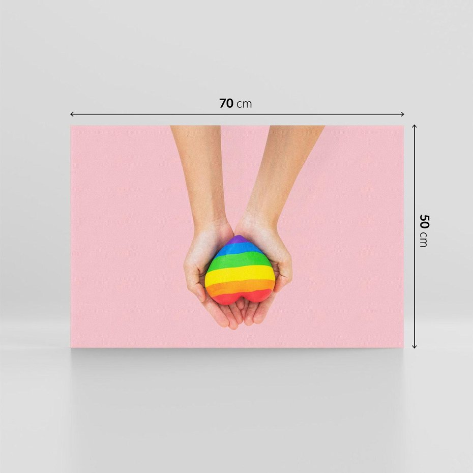 Obraz na płótnie 70x50 - Miłość na Dłoniach - zdjęcie, dłonie trzymają ulepione tęczowe serce