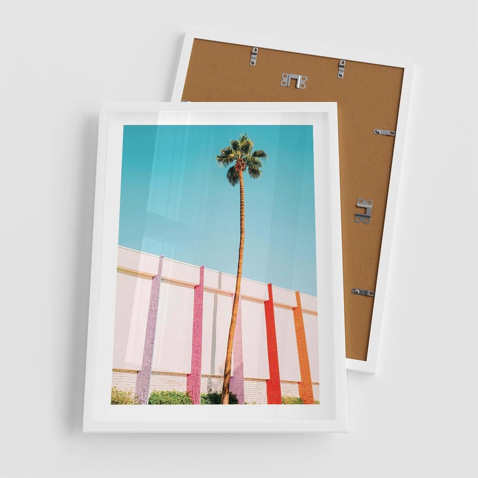 Plakat w ramie 50x70 - Tropikalny Kontrast - palma na tle błękitnego nieba, kolorowy mur - rama biała