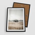 Plakat w ramie 50x70 - Wiejska Idylla - stary drewniany dom w polu suchej trawy, fotografia - rama czarna