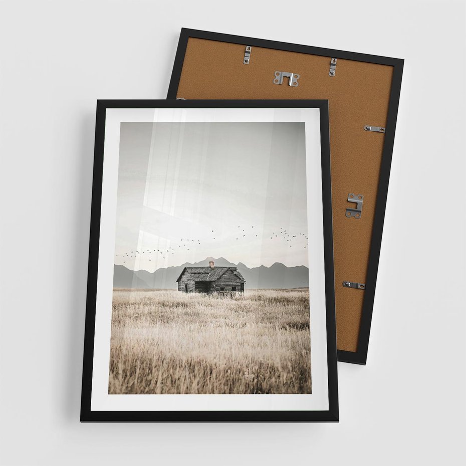 Plakat w ramie 50x70 - Wiejska Idylla - stary drewniany dom w polu suchej trawy, fotografia - rama czarna