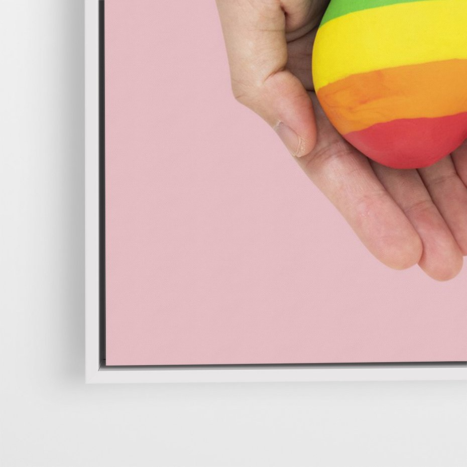 Obraz w ramie 80x120 - Miłość na Dłoniach - zdjęcie, dłonie trzymają ulepione tęczowe serce - rama biała