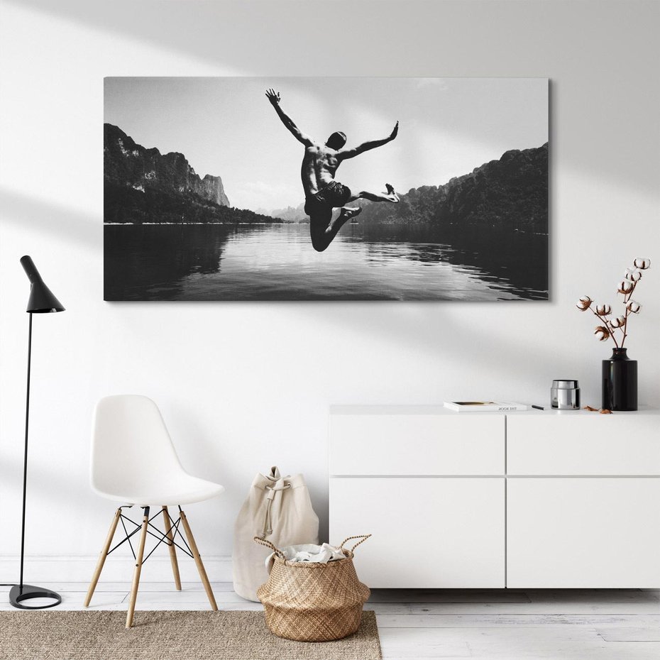 Obraz na płótnie 140x70 - Beztroska Chwila - czarno biała fotografia, mężczyzna wesoło wskakuje do keziora w górach