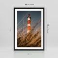 Plakat w ramie 50x70 - Magia nadmorskiego światła - latarnia morska, ujęcie z za trawy - rama czarna