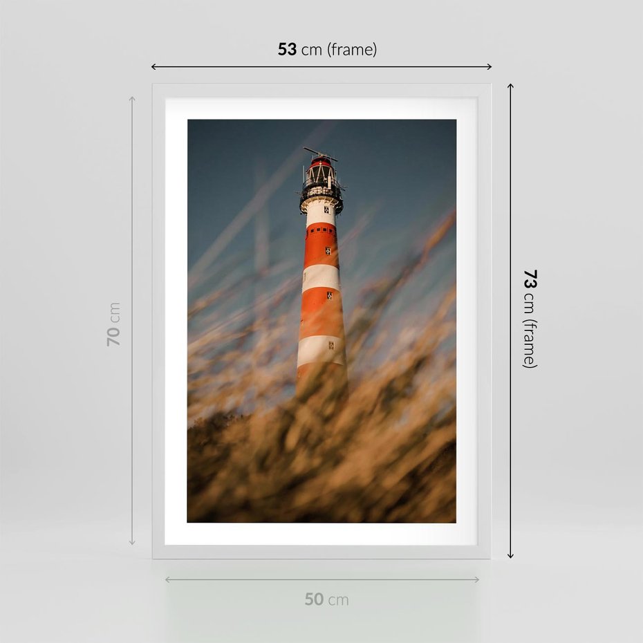Plakat w ramie 50x70 - Magia nadmorskiego światła - latarnia morska, ujęcie z za trawy - rama biała