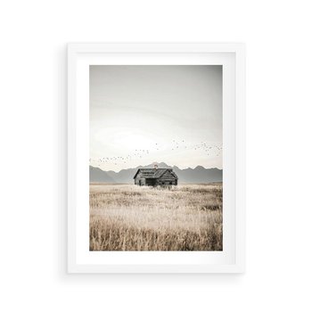 Plakat w ramie 50x70 - Wiejska Idylla - stary drewniany dom w polu suchej trawy, fotografia - rama biała