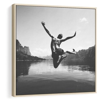 Obraz w ramie 50x50 - Beztroska Chwila - czarno biała fotografia, mężczyzna wesoło wskakuje do keziora w górach - rama drewno