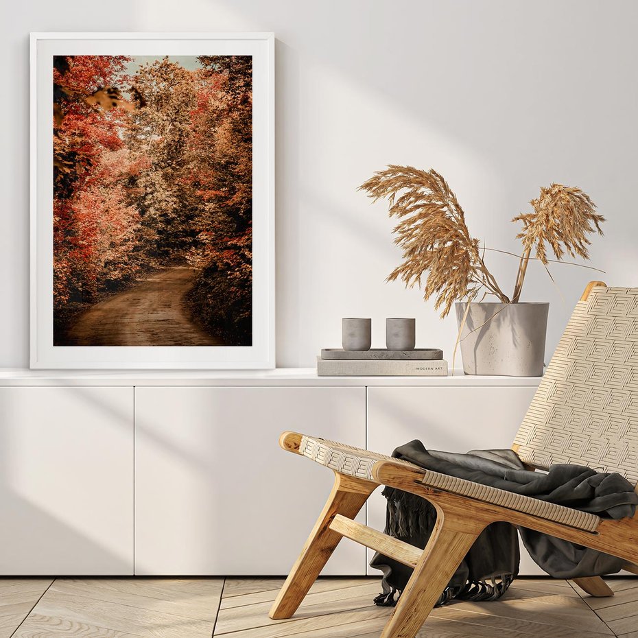 Plakat w ramie 30x40 - Obraz przedstawia jesienne drzewa i czerwone liście na ścieżce w lesie. Ta sceneria doskonale oddaje urok i kolorystykę jesieni w lesie. - las, jesień - rama biała