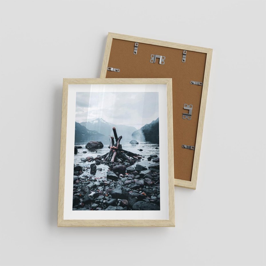 Plakat w ramie 30x40 - To ujęcie jeziora w górach z zgaszonym ogniskiem nad brzegiem, tworząc atmosferę spokoju i refleksji w otoczeniu przyrody. - jezioro w górach, zgaszone ognisko - rama drewno