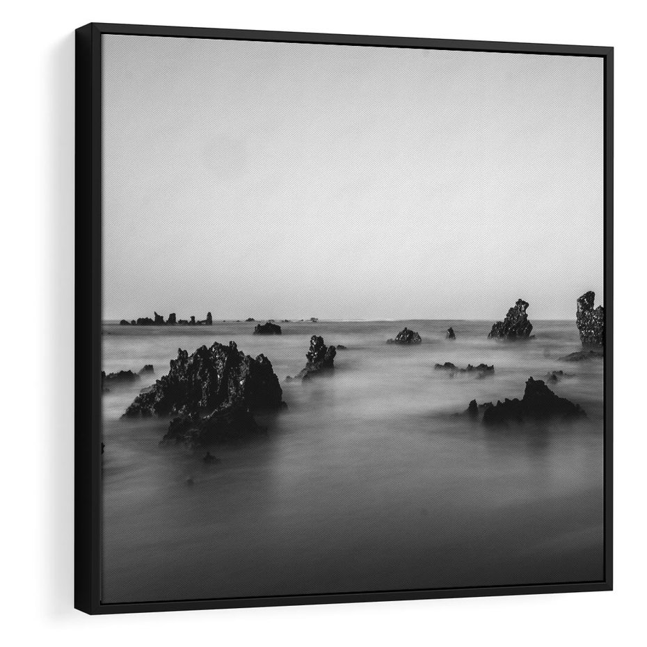 Obraz w ramie 50x50 - Harmonia świateł i cieni - zamglona dzika plaża, skały na plaży - rama czarna
