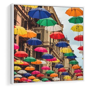 Obraz w ramie 80x80 - Barwna symfonia wyobraźni - fotografia, kolorowe parasolki podwieszone nad ulicą - rama biała