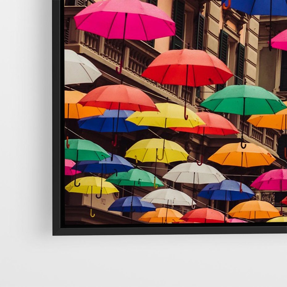 Obraz w ramie 100x70 - Barwna symfonia wyobraźni - fotografia, kolorowe parasolki podwieszone nad ulicą - rama czarna