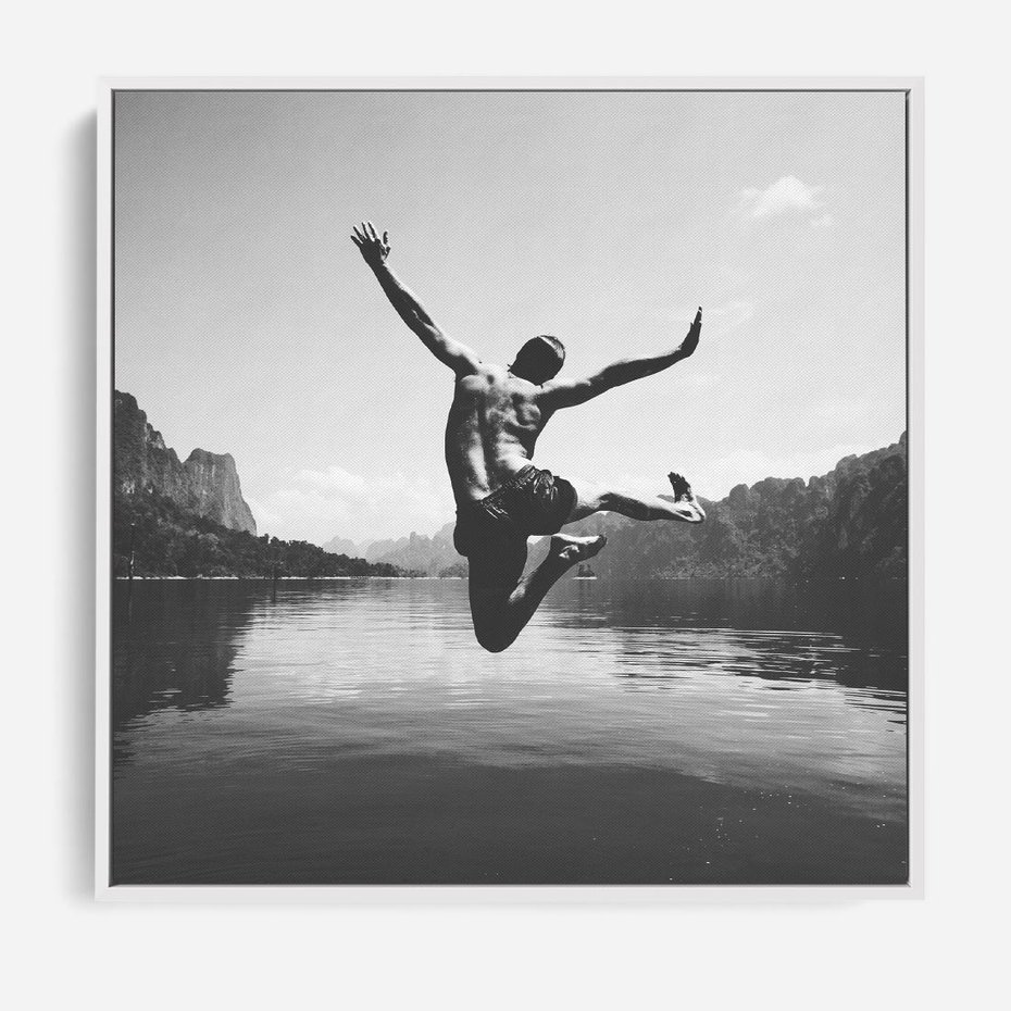 Obraz w ramie 50x50 - Beztroska Chwila - czarno biała fotografia, mężczyzna wesoło wskakuje do keziora w górach - rama biała