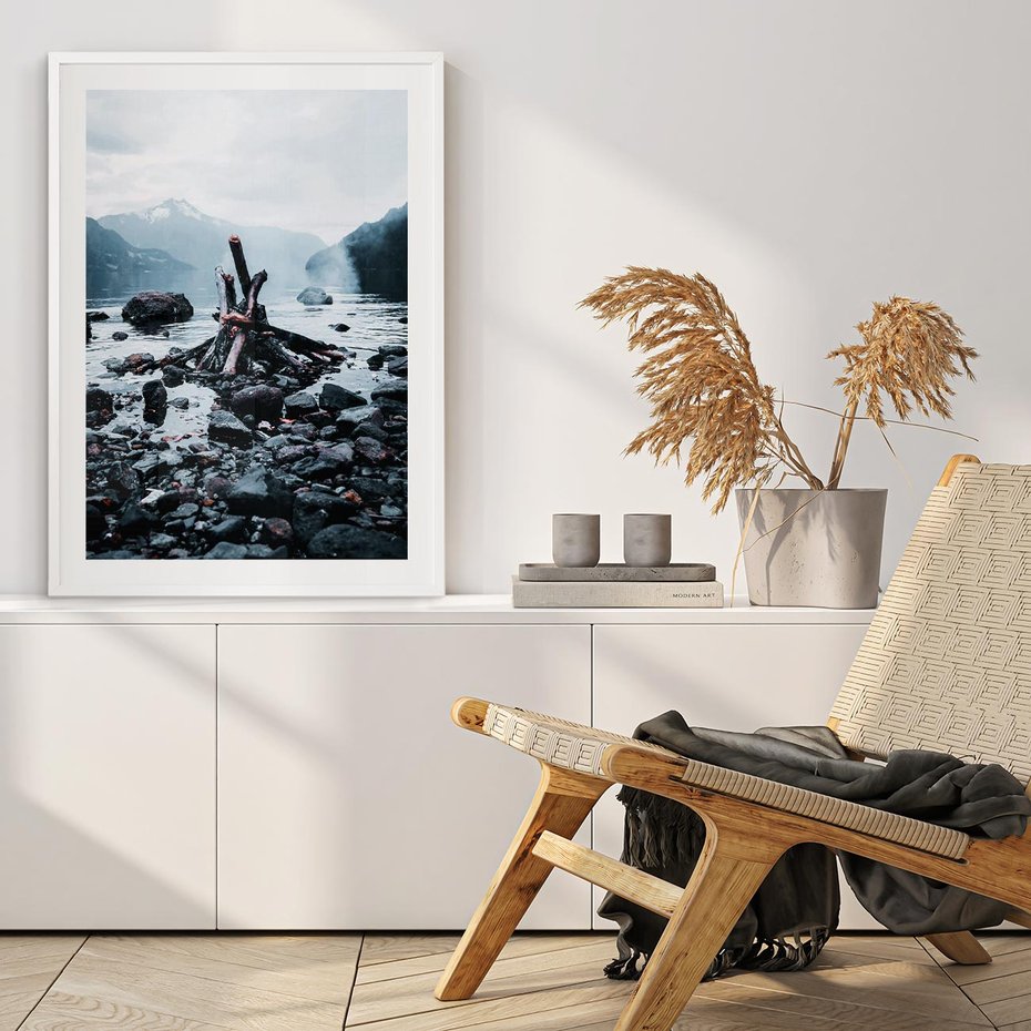 Plakat w ramie 40x50 - To ujęcie jeziora w górach z zgaszonym ogniskiem nad brzegiem, tworząc atmosferę spokoju i refleksji w otoczeniu przyrody. - jezioro w górach, zgaszone ognisko - rama biała