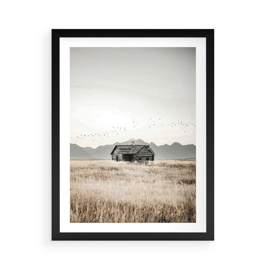 Plakat w ramie 50x70 - Wiejska Idylla - stary drewniany dom w polu suchej trawy, fotografia - rama czarna
