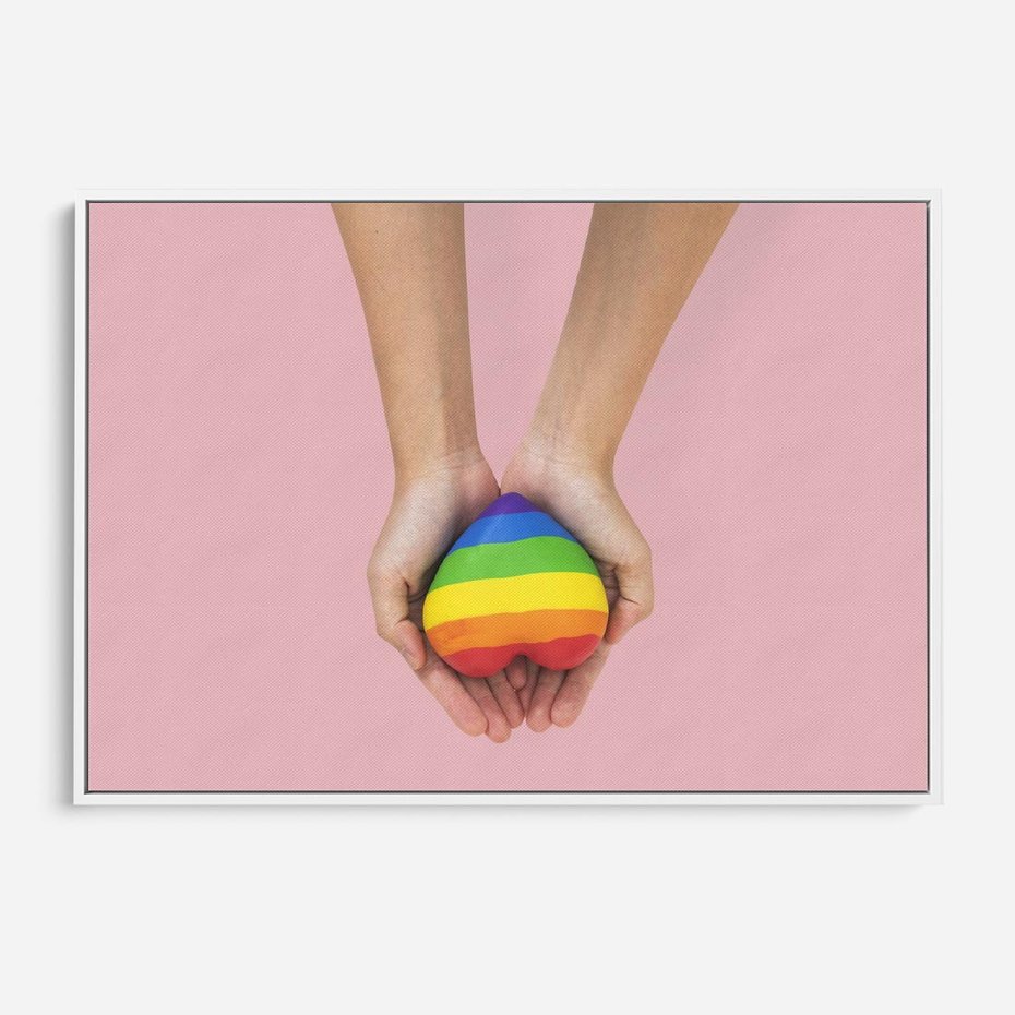 Obraz w ramie 70x50 - Miłość na Dłoniach - zdjęcie, dłonie trzymają ulepione tęczowe serce - rama biała
