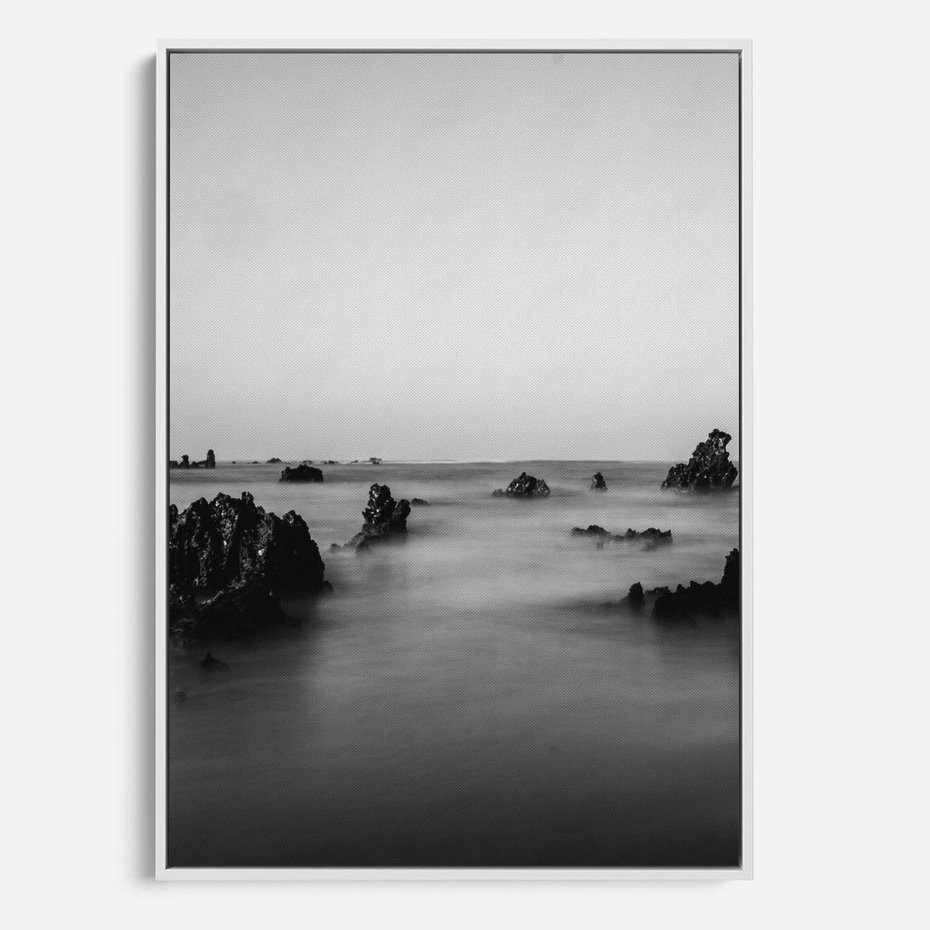 Obraz w ramie 80x120 - Harmonia świateł i cieni - zamglona dzika plaża, skały na plaży - rama biała