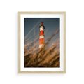 Plakat w ramie 30x40 - Magia nadmorskiego światła - latarnia morska, ujęcie z za trawy - rama drewno