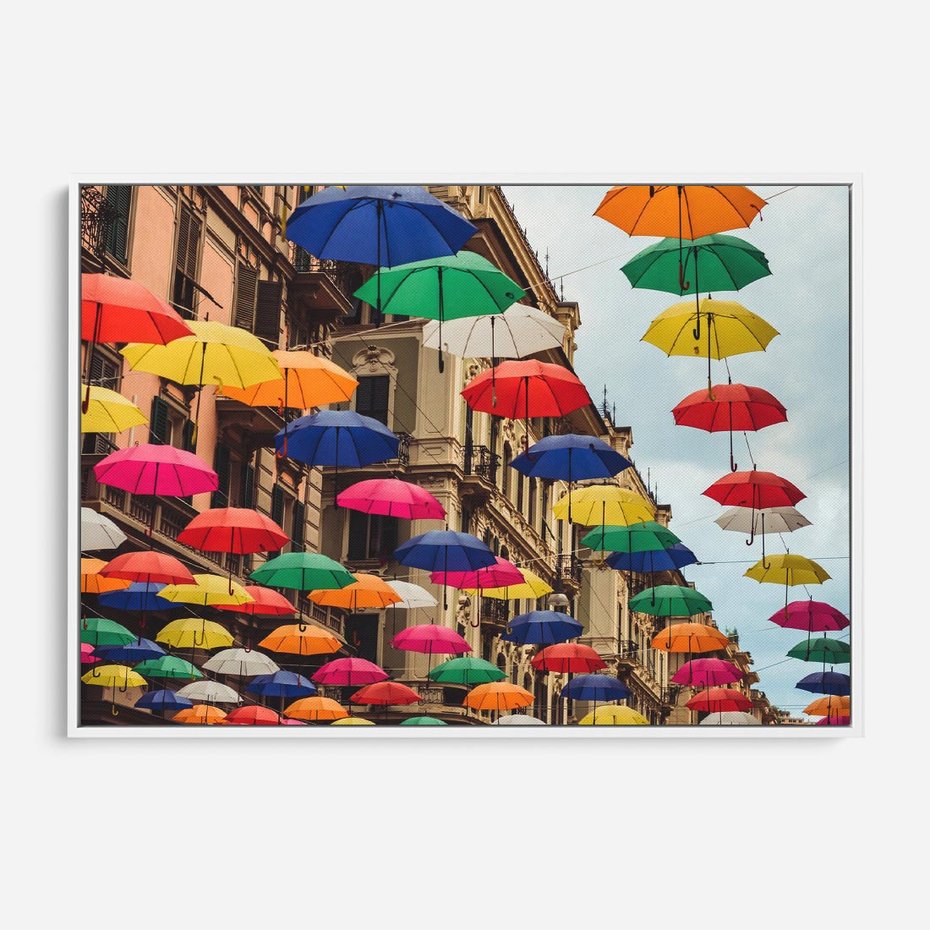 Obraz w ramie 120x80 - Barwna symfonia wyobraźni - fotografia, kolorowe parasolki podwieszone nad ulicą - rama biała