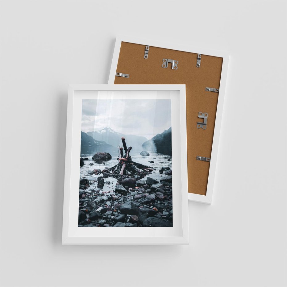 Plakat w ramie 30x40 - To ujęcie jeziora w górach z zgaszonym ogniskiem nad brzegiem, tworząc atmosferę spokoju i refleksji w otoczeniu przyrody. - jezioro w górach, zgaszone ognisko - rama biała