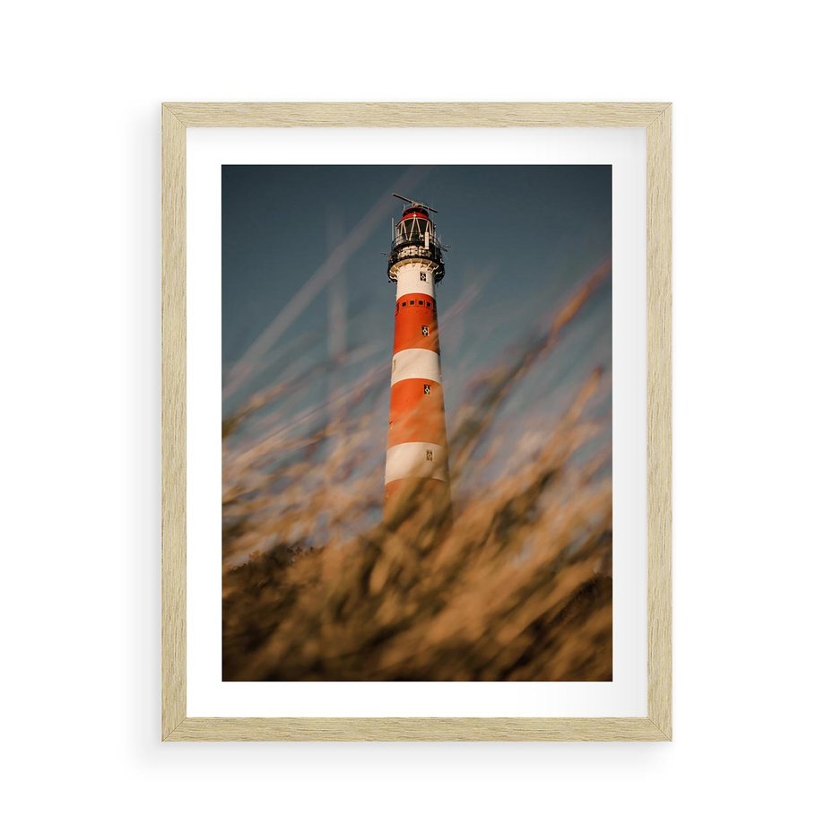 Plakat w ramie 40x50 - Magia nadmorskiego światła - latarnia morska, ujęcie z za trawy - rama drewno