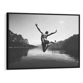 Obraz w ramie 70x50 - Beztroska Chwila - czarno biała fotografia, mężczyzna wesoło wskakuje do keziora w górach - rama czarna