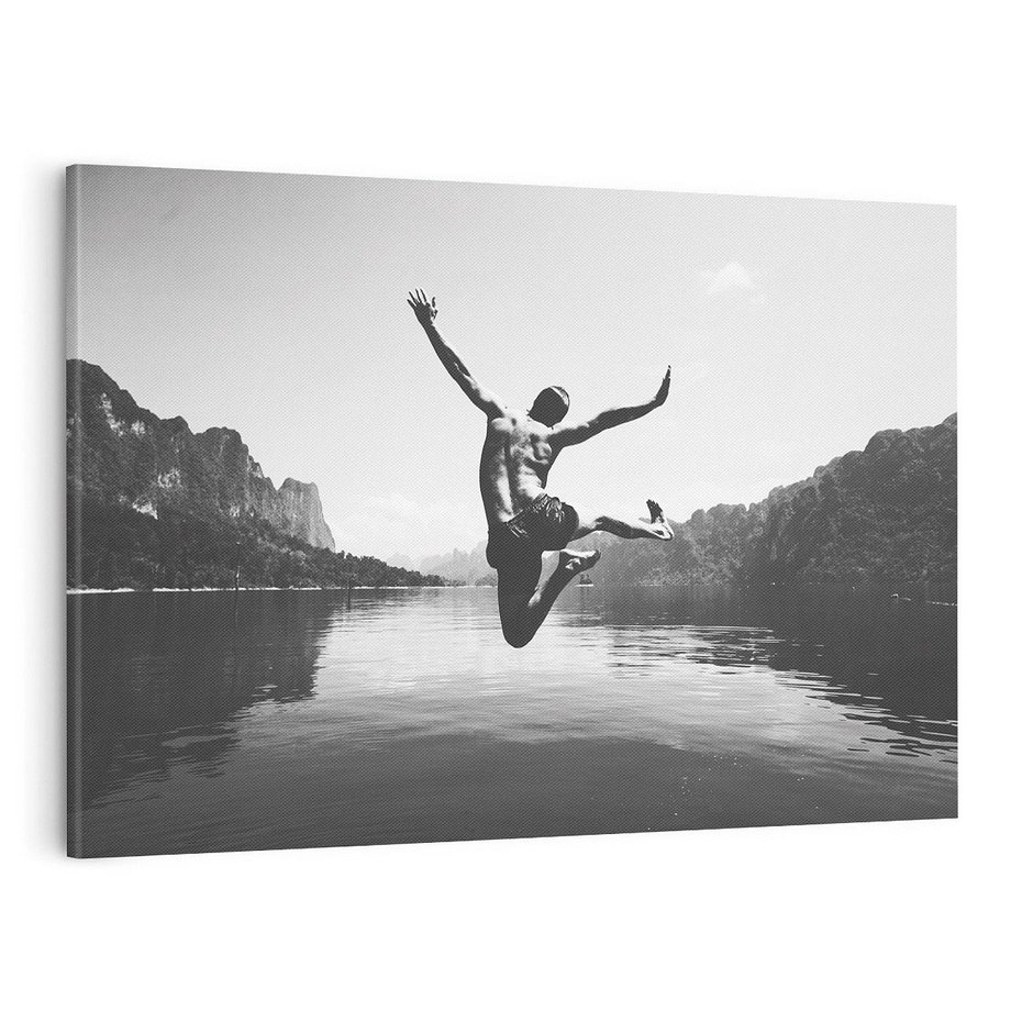 Obraz na płótnie 70x50 - Beztroska Chwila - czarno biała fotografia, mężczyzna wesoło wskakuje do keziora w górach