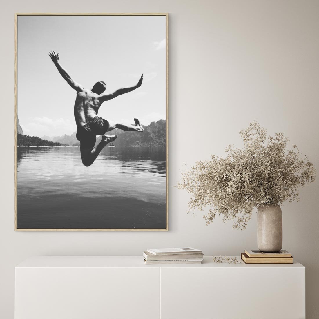 Obraz w ramie 80x120 - Beztroska Chwila - czarno biała fotografia, mężczyzna wesoło wskakuje do keziora w górach - rama drewno