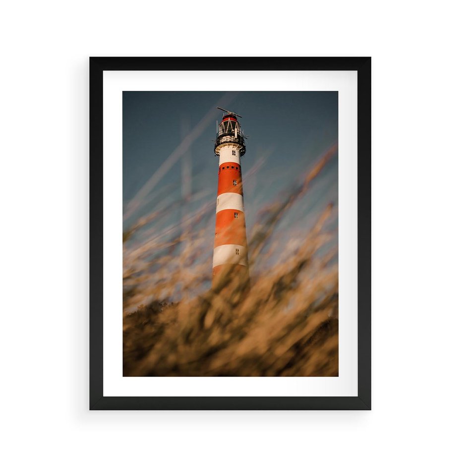 Plakat w ramie 40x50 - Magia nadmorskiego światła - latarnia morska, ujęcie z za trawy - rama czarna
