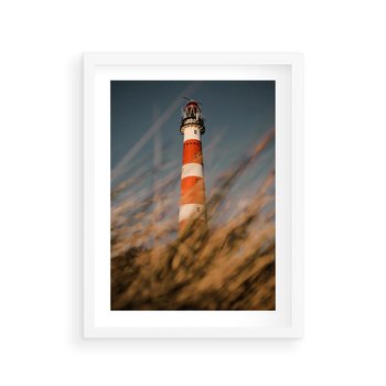 Plakat w ramie 30x40 - Magia nadmorskiego światła - latarnia morska, ujęcie z za trawy - rama biała