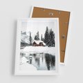 Plakat w ramie 50x70 - Urok Zimowego Krajobrazu - domek w górach, zima - rama biała