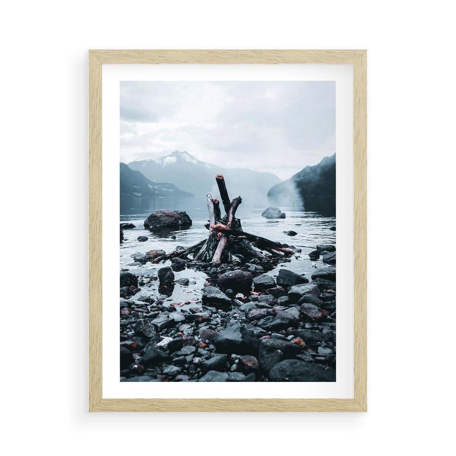 Plakat w ramie 50x70 - To ujęcie jeziora w górach z zgaszonym ogniskiem nad brzegiem, tworząc atmosferę spokoju i refleksji w otoczeniu przyrody. - jezioro w górach, zgaszone ognisko - rama drewno