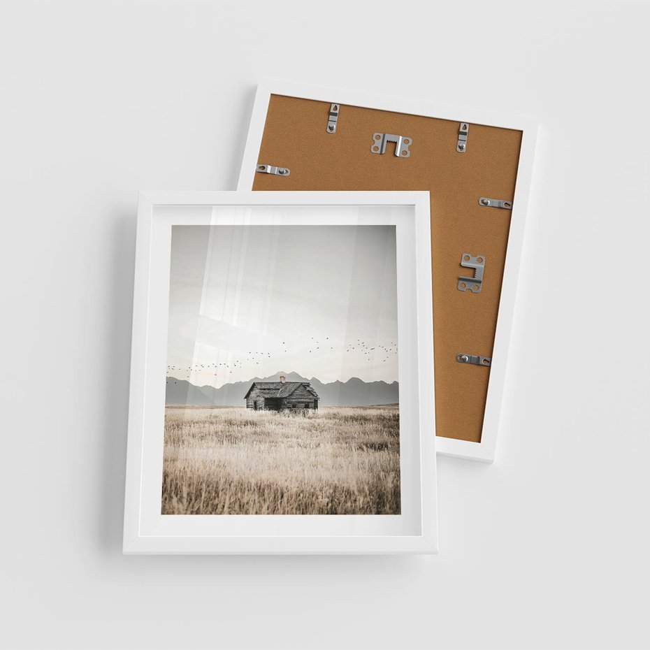 Plakat w ramie 40x50 - Wiejska Idylla - stary drewniany dom w polu suchej trawy, fotografia - rama biała